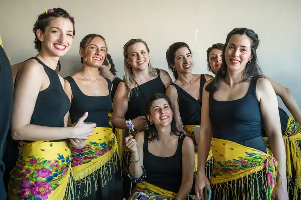 Dancers in black tops with yellow embroidered scarves at the waist, before the show