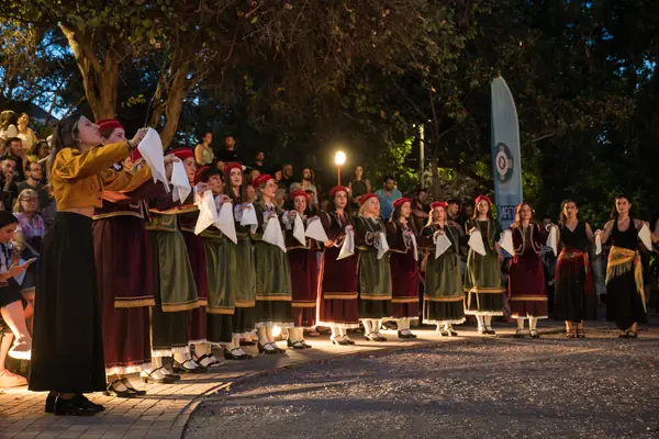A long line of dancers in traditional dress, at night