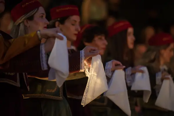 Dancers in red caps holding white handkerchiefs