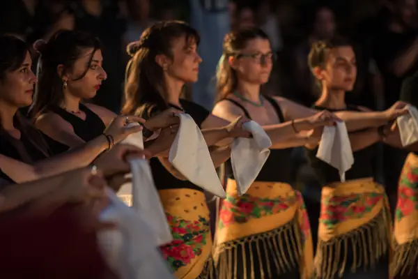 Dancers in a row holding white handkerchiefs