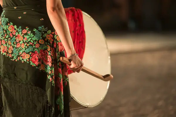 Detail: an embroidered skirt and a drum