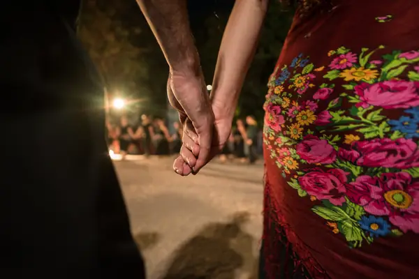 Detail: two joined hands and a flowered skirt