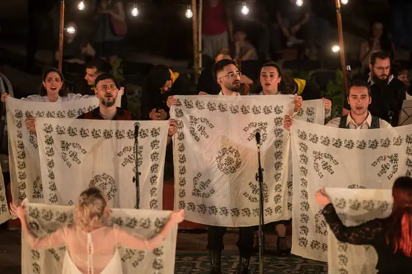Dancers holding up large embroidered cloths