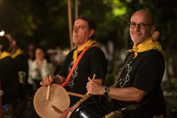 Two musicians in yellow scarves playing drums